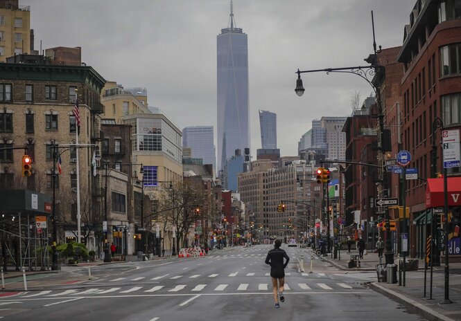 Ein einsamer Jogger auf der 7th Avenue in New York, USA. Die Straßen sind leer. Am Ende der Straße sieht man Hochhäuser.