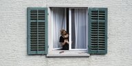 Eine junge Frau klatscht aus ihrem Fenster