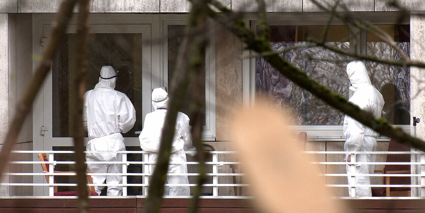 Menschen in Schutzkleidung stehen auf einem Balkon