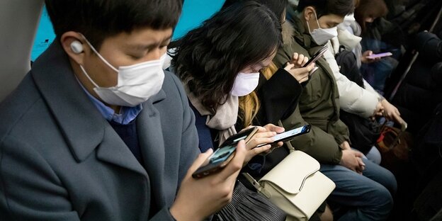 Fahrgäste mit Schutzmasken und Smartphones
