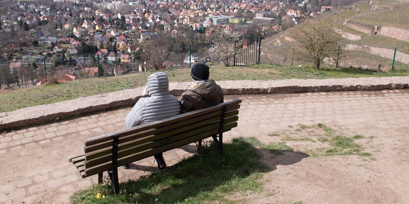 Sachsen, Radebeul: Zwei Passanten sitzen am Bismarckturm auf einer Bank. Zur Eindämmung des Coronavirus verbietet Sachsen alle Ansammlungen ab drei Personen in der Öffentlichkeit.