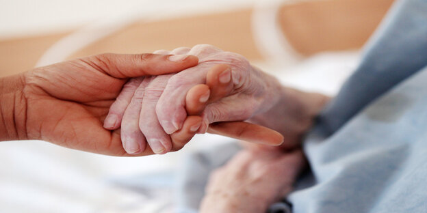 EIne Hand hält die Hand eines alten Menschen EIne Hand hält die Hand eines alten Menschen
