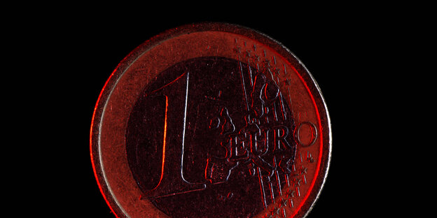 Ein rot angeleuchtete Euromünze vor schwarzem Hintergrund. Ein rot angeleuchtete Euromünze vor schwarzem Hintergrund.