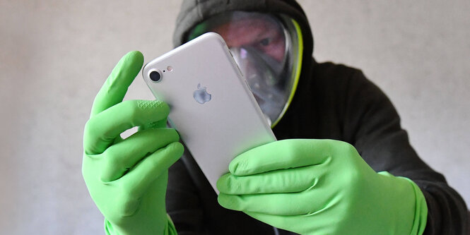 Ein Mann mit Handschuhen hält ein Smartphone.