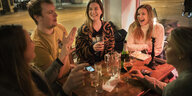 Eine Gruppe von Schwedinnen und Schweden sitzt lachend an einem Kneipentisch