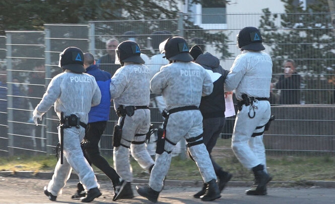 Thüringen, Suhl: Polizisten in Schutzkleidung sind bei der Landeserstaufnahmestelle für Asylbewerber in Suhl im Einsatz