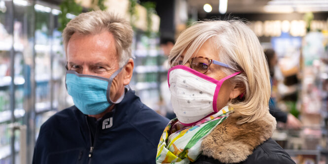 Ein Mann und eine Frau tragen in einem Supermarkt Mundschutz