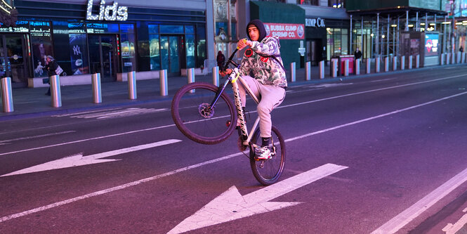 Ein Mann macht einen Wheelie auf einer leeren Starße.