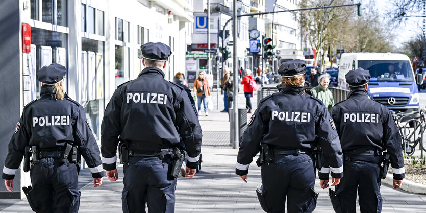 Rückenansicht von vier Polizisten auf der Streife