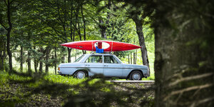 Ein Auto steht im Wald mit einem Kanu auf dem Dach