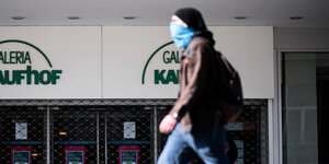 Ein Mann geht mit Maske am Eingang der Filiale der Kaufhauskette Kaufhof in Essen vorbei.