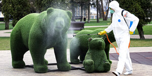Ein Arbeiter in Schutzanzug desinfiziert eine Bärenstatue.