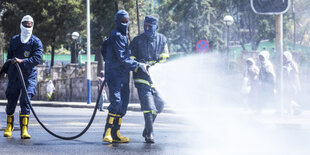 Feuerwehrmänner mit Schutzanzügen versprühen eine Flüssigkeit