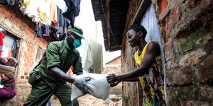 Ein ugandischer Soldat übergibt einer Frau Nahrungsmitel