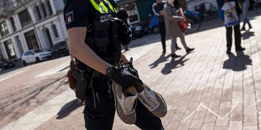 Ein Polizist trägt Schuhe weg