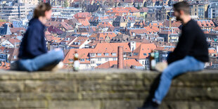 Ein Mann und eine Frau sitzen auf einer Mauer im Freien mit Abstand