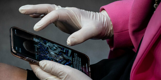 Eine Frau fasst ihr Smartphone mit Handschuhen an
