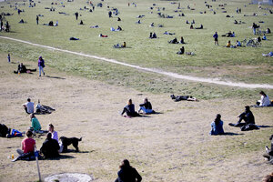Viele menschen sitzen vereinzelt in einem Park Viele menschen sitzen vereinzelt in einem Park