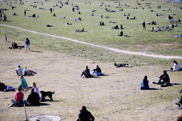 Viele menschen sitzen vereinzelt in einem Park