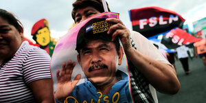 eine Frau trägt ein Plakat mit dem Portrait von Daniel Ortega auf eine Demonstration am Frauentag