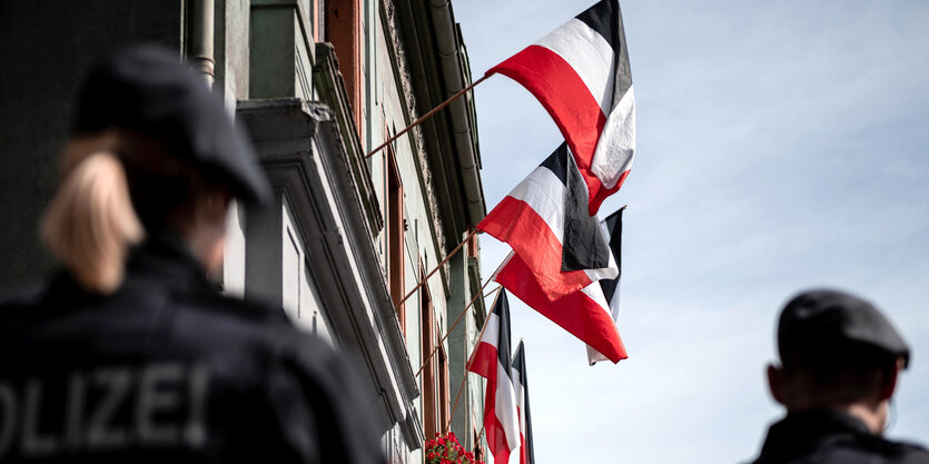 Reichsfahnen hängen an den Fenstern der Häuser an der Emscherstraße in Dortmund-Dorstfeld. im Vordergrund sind PolizistInnen zu sehen