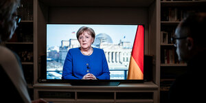 Fernsehbildschirm auf dem Angela Merkel zu sehen ist. Sie spricht