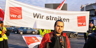 Özay Tarim vor Transparent mit der Aufschrift "Wir streiken"