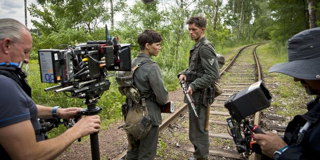 Filmteam und zwei Schauspieler in Uniformen in einem Wald