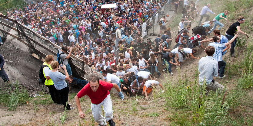 Menschen flüchten aus einer vollen Unterführung eine Böschung hinauf