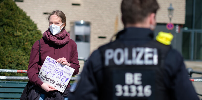 Frau mit Mundschutzmaske hält Pappschild mit der Forderung "Aufnahme jetzt!"