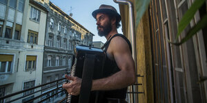 Ein Mann steht auf einem Balkon und spiel Akkordeon