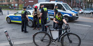 Polizisten kontrollieren einen Mann und fotografieren sein Fahrrad