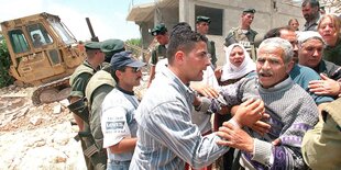 Gerangel mehrere Personen im Vordergrund, im Hintergrund ein Bulldozer, der ein Haus abreißt