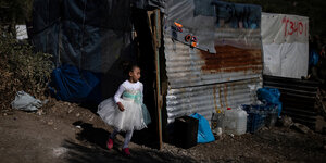 Ein Kind in weißem Kleid geht an einer Hütte vorbei