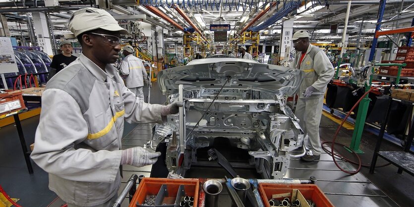 Männer arbeiten in einem Autowerk von Renault bei Paris, Frankreich. Sie tragen Schutzkleidung.