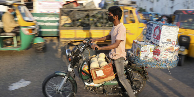 Mann auf Roller mit Mundschutzmaske in Indien Mann auf Roller mit Mundschutzmaske in Indien