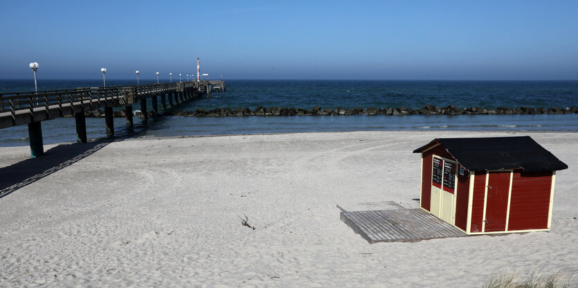 Leerer Strand mit einer Holzhütte und einer Seebrücke