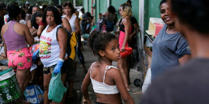 Mädchen in Rio de Janeiro dreht sich um. Sie wartet auf Reste, die der Fischverkäufer verschenken will