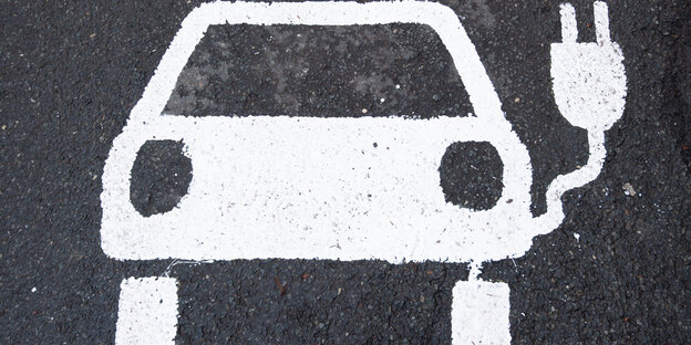 Ein Symbol eines Elektroautos markiert einen Parkplatz neben einer E-Ladesäule
