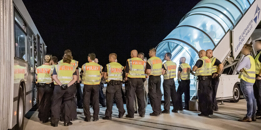 Polizeibeamte begleiten einen Afghanen auf dem Flughafen Leipzig-Halle in ein Charterflugzeug.