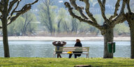 Zwei Menschen sitzen auf einer Parkbank in Corona-Zeiten