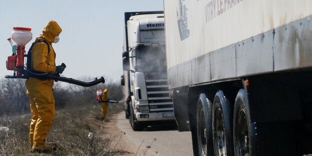 Ein Mann im Schutzanzug desinfiziert einen Lastwagen mit Hilfsgütern