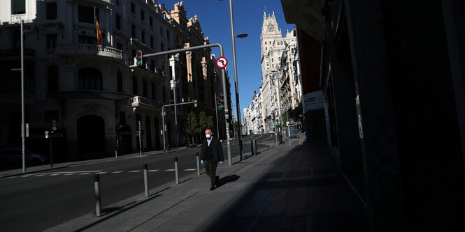 Ein Mann läuft mit einem Mundschutz in einer sonst leeren Straße in Madrid