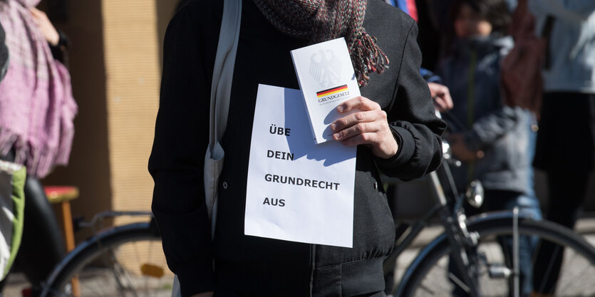 Eine Person hält ein Grundgesetz in der Hand