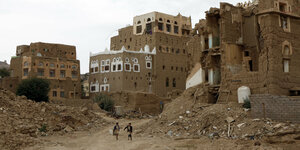 Zwei Kinder passieren die Trümmer von Häusern im Jemen.
