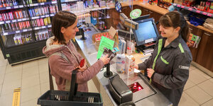 Eine Kundin eines "Konsum" Supermarktes bezahlt mit einer EC-Karte hinter einer Scheibe
