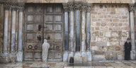 Der verschlossene Eingang der Grabeskirche- Davor steht ein Mann mit Schutzkleidung - etwas weiter entfernt ein Mann mit Hut und Mundschutz