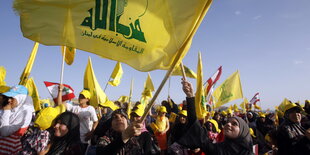 Frauen schwenken eine große Fahne der Hisbollah.