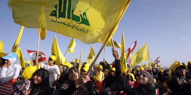 Frauen schwenken eine große Fahne der Hisbollah.
