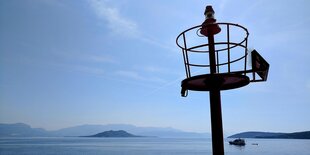 ein Aussichtsturm vor einer Bucht unter blauem Himmel, es sind kaum Schiffe zu sehen